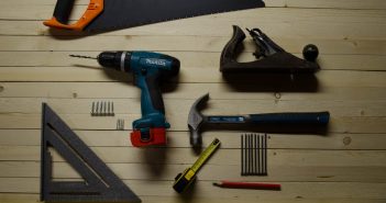 Comment choisir sa perceuse visseuse ? outils de bricolage sur un sol en bois avec scie equerre perceuse marteau vis crayon metre