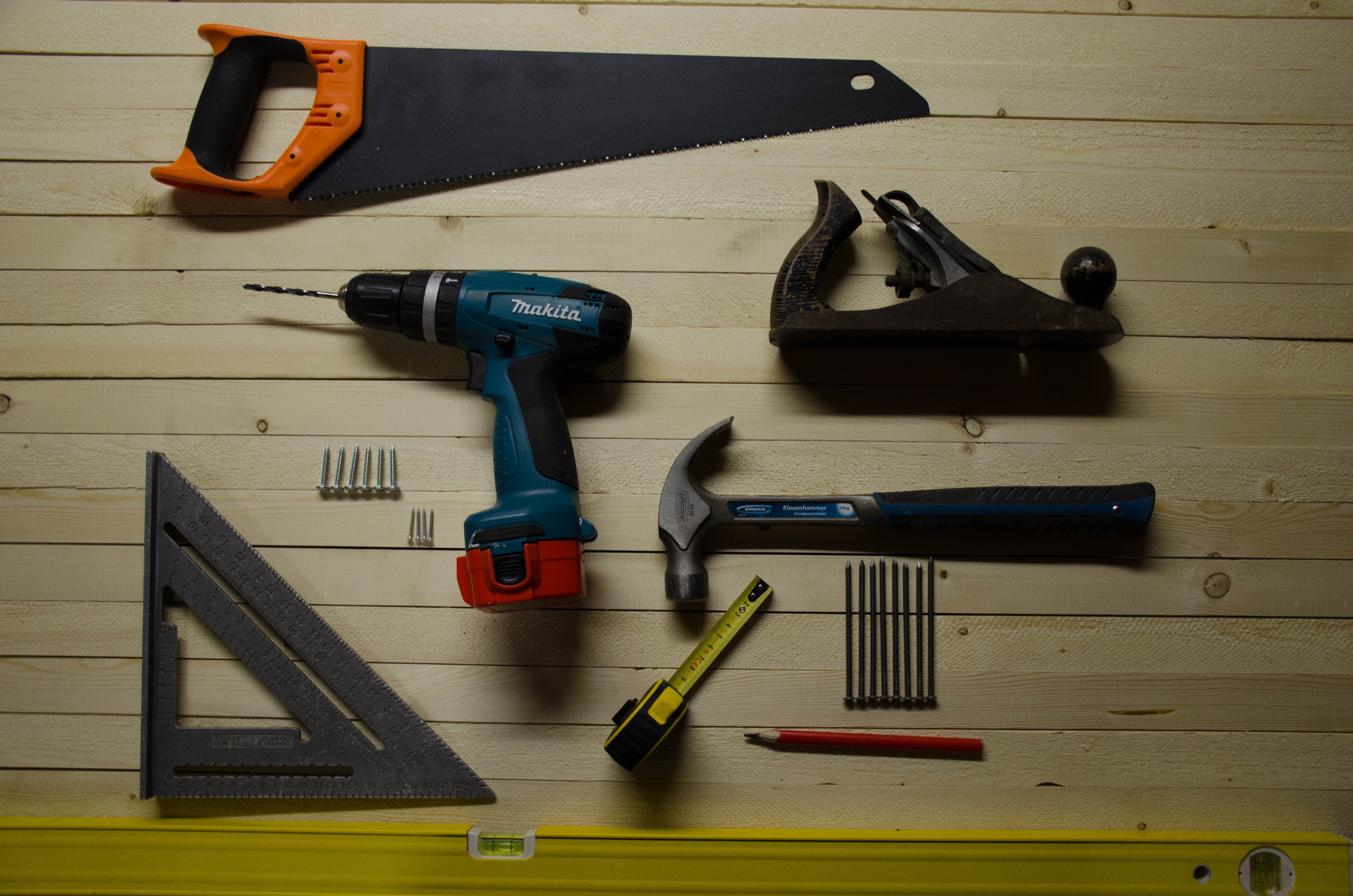 outils de bricolage sur un sol en bois avec scie equerre perceuse marteau vis crayon metre