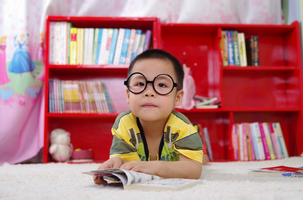 Un enfant qui lit devant une étagère dans sa chambre