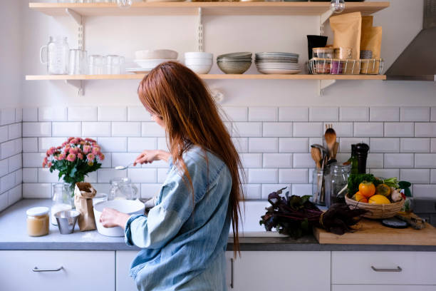 Jeune femme en train de cuisiner dans sa cuisine bien aménagée