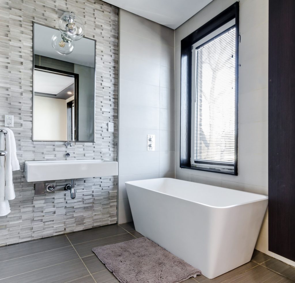salle de bain moderne avec carrelage au sol et carrelage mural baignoire rectangle et miroir au dessus de vasque